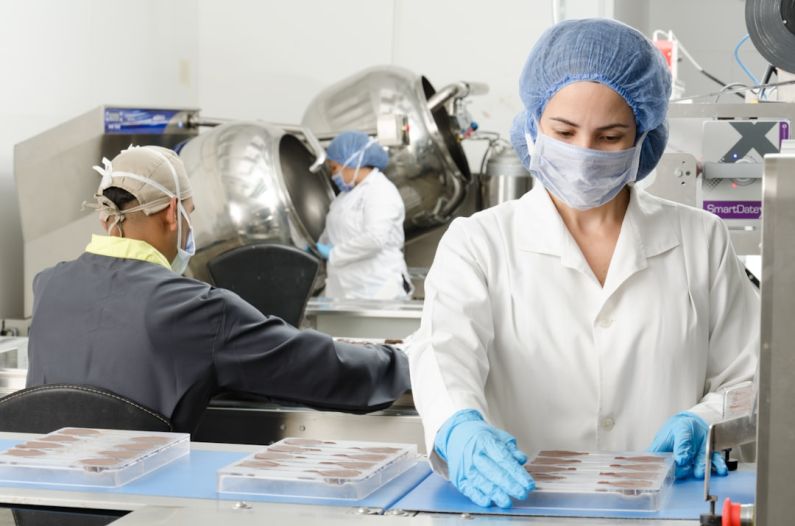 Food Safety - three people inside factory wearing masks and coats