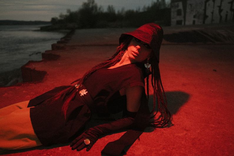 Japanese Bands - woman in black long sleeve shirt and red hijab sitting on brown sand during daytime