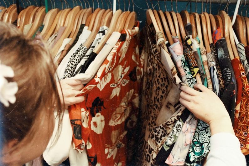 Fashion Trends - person holding assorted clothes in wooden hanger