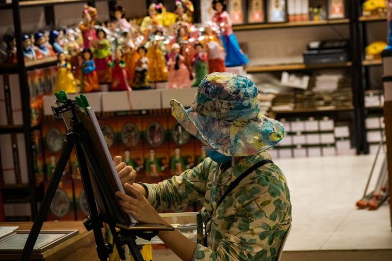 Japanese Artists - a woman in a hat is painting on a easel