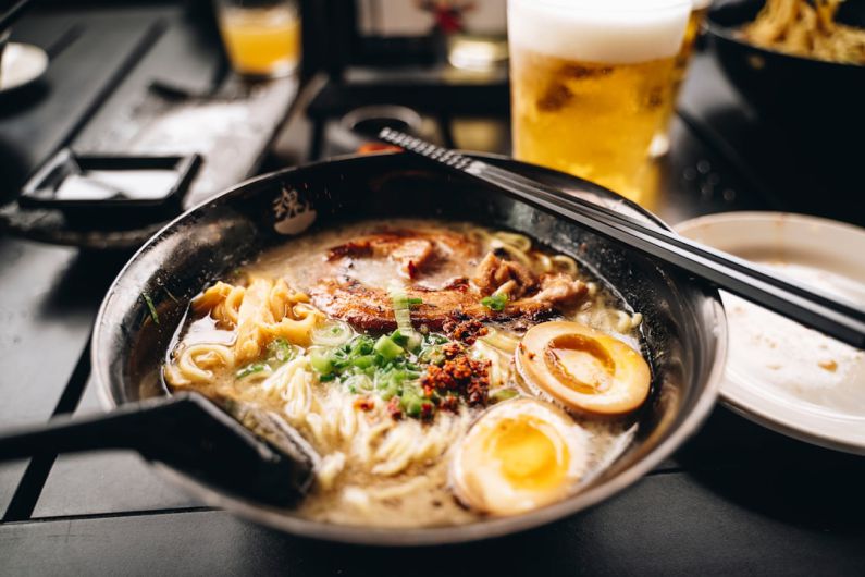 Ramen - a bowl of ramen with chopsticks and a glass of beer